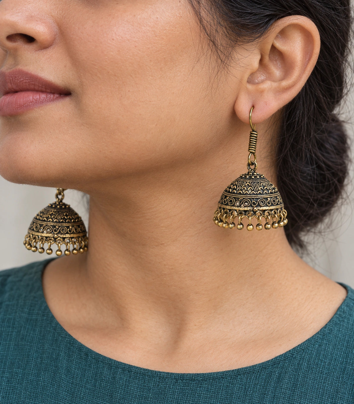 JIMIKI Antique Gold Chevron Scroll Jhumka Earrings - Antique Gold earring worn with a clear view of the design #color_antique-gold