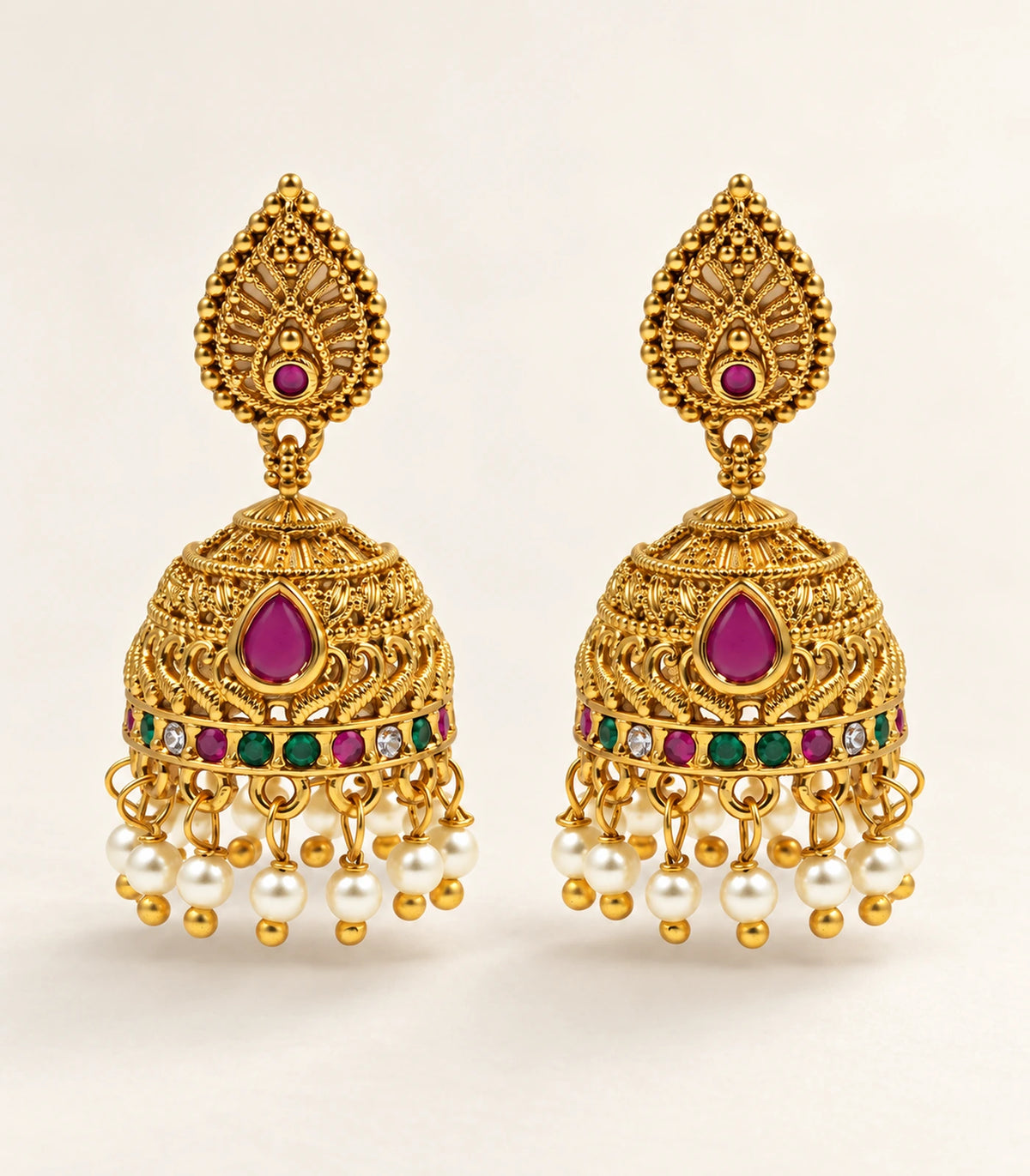 Matching pair of magenta multicolour pearl jhumka earrings on a warm neutral surface