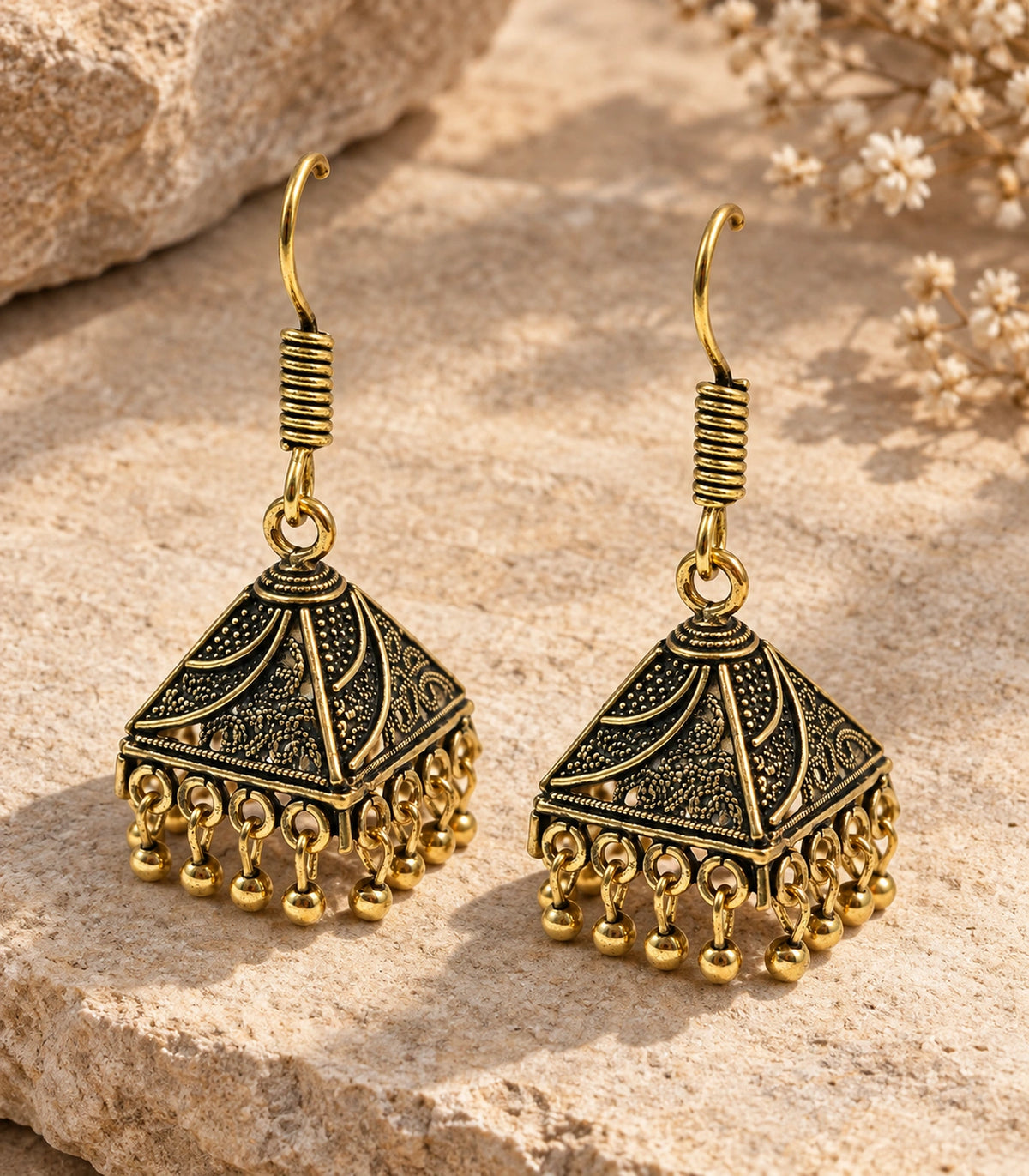 JIMIKI Antique Gold Paisley Pyramid Jhumka Earrings - styled flatlay of the matching earrings #color_antique-gold