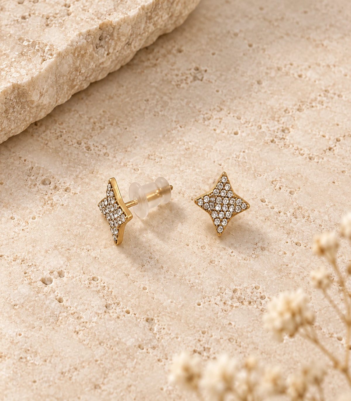 JIMIKI antique gold-tone four-point star stud earrings, matching pair on a textured stone surface with push-back fastening visible #color_antique-gold