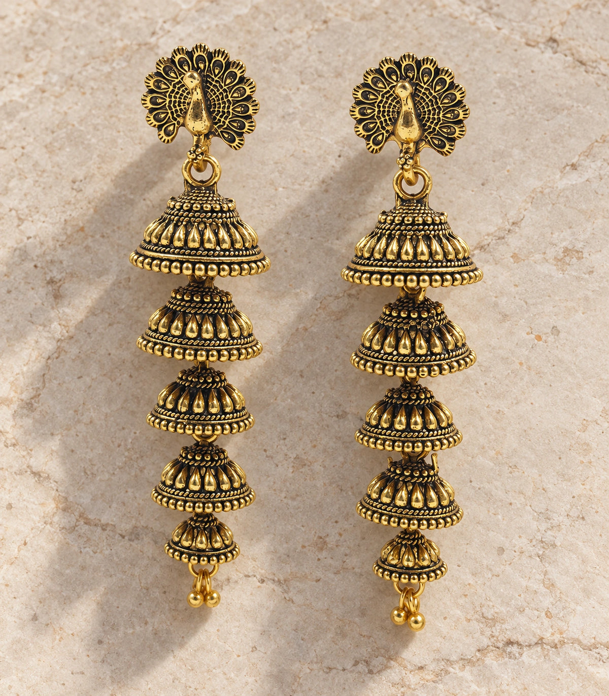 JIMIKI Peacock Five Tier Jhumka Earrings in Antique Gold - editorial flatlay #color_antique-gold