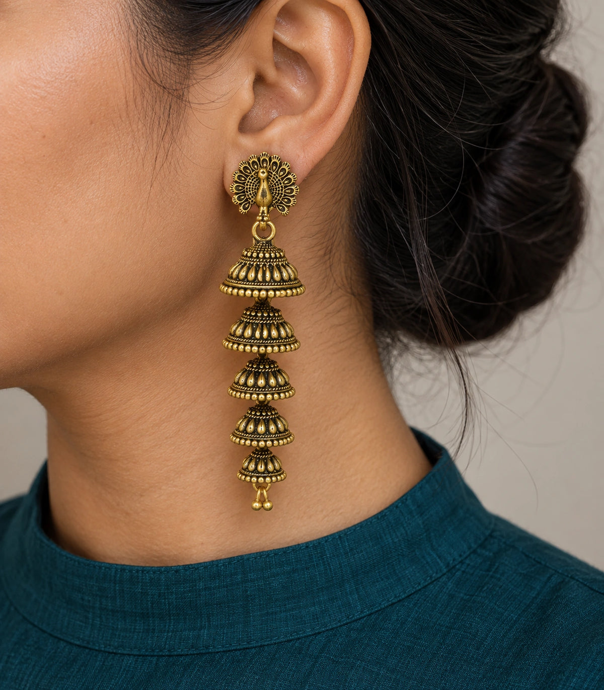 JIMIKI Peacock Five Tier Jhumka Earrings in Antique Gold - worn styling view #color_antique-gold