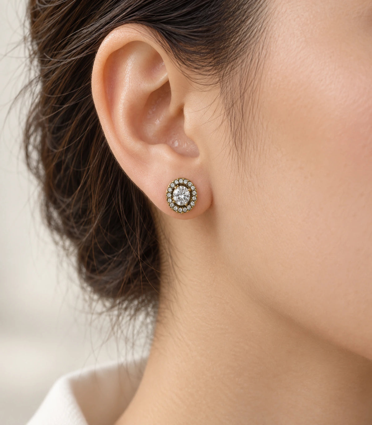 JIMIKI Antique Gold Round Crystal Halo Stud Earrings, single stud worn with swept-back hair and soft warm lighting #color_antique gold