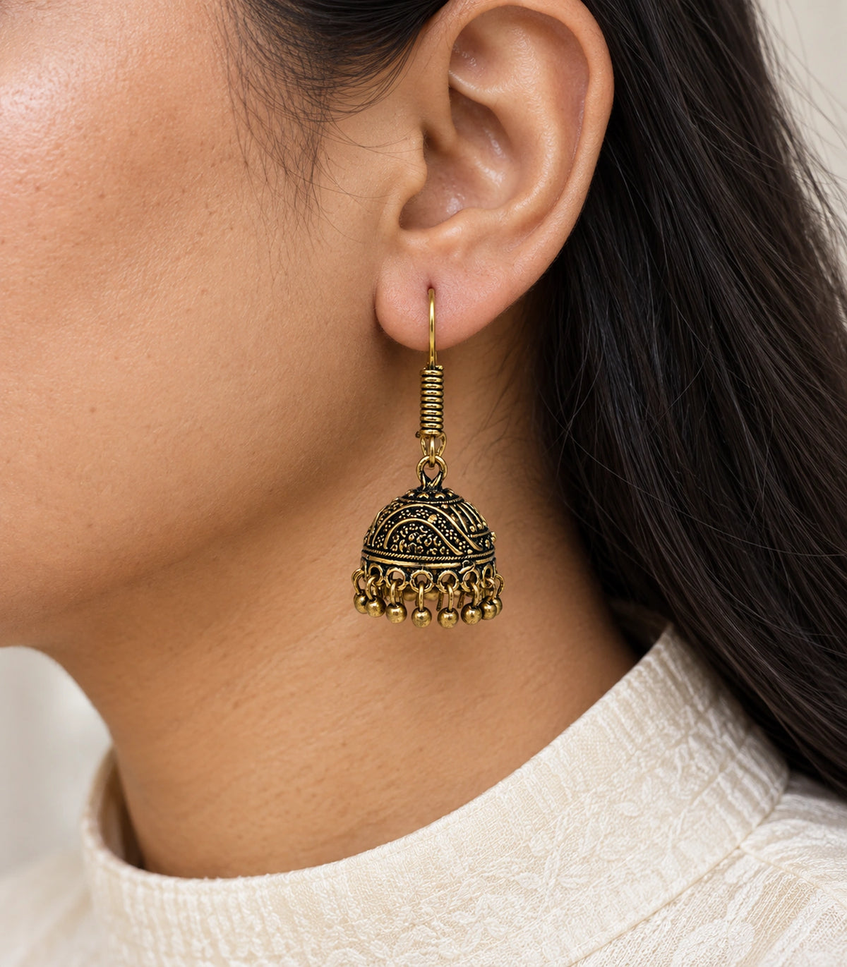Antique gold-tone wave scroll hook jhumka worn with an ivory top #color_antique-gold