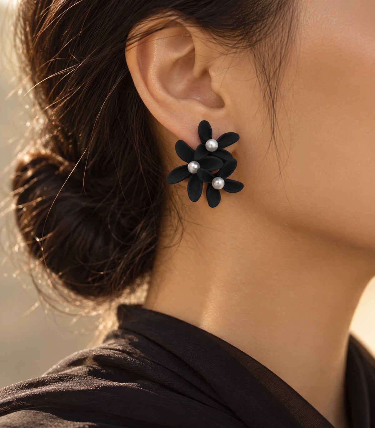 JIMIKI Black cascading floral cluster stud earrings, worn with softly lit editorial styling #color_black