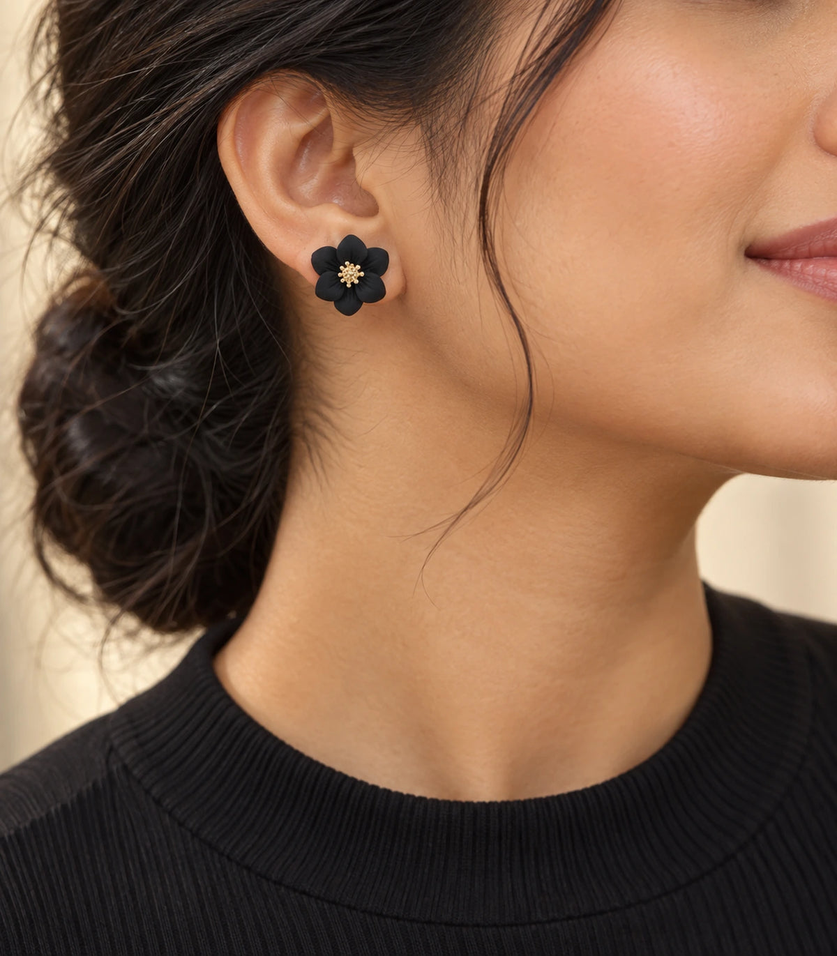 JIMIKI Black compact six petal flower stud earrings, styled portrait showing the flower stud at the ear #color_black