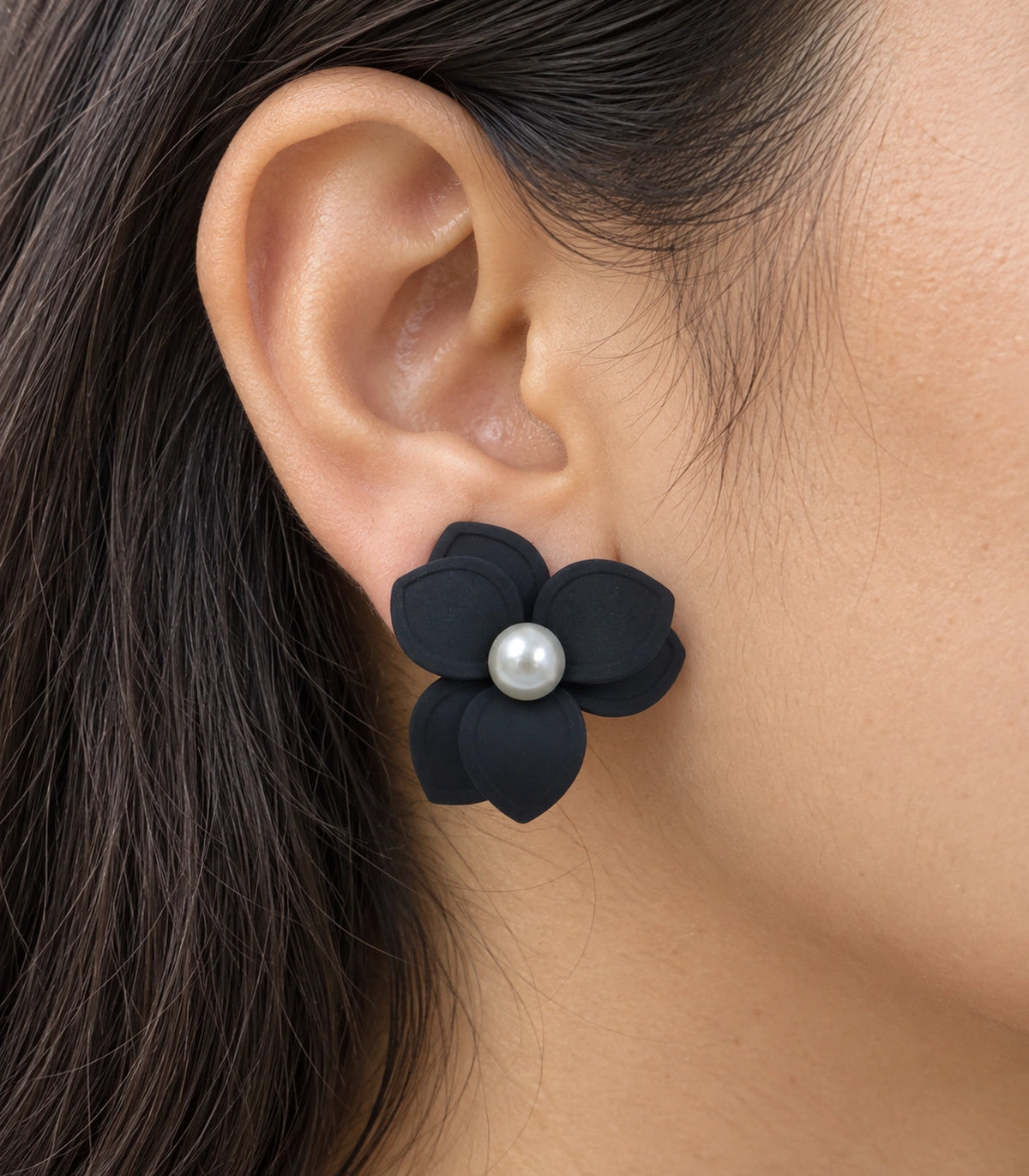 JIMIKI Black Triple Petal Pearl Flower Stud Earrings - layered petals and pearl-style centre worn close-up #color_black