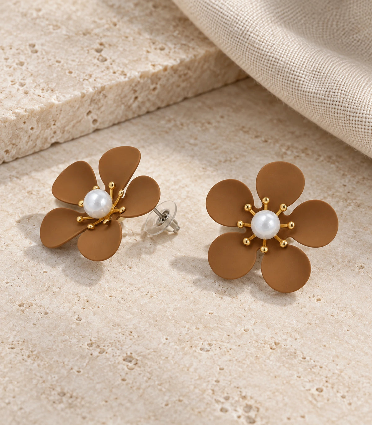 JIMIKI camel five-petal flower stud earrings with pearl-effect centre, matching flower stud pair in an editorial flat lay #color_camel