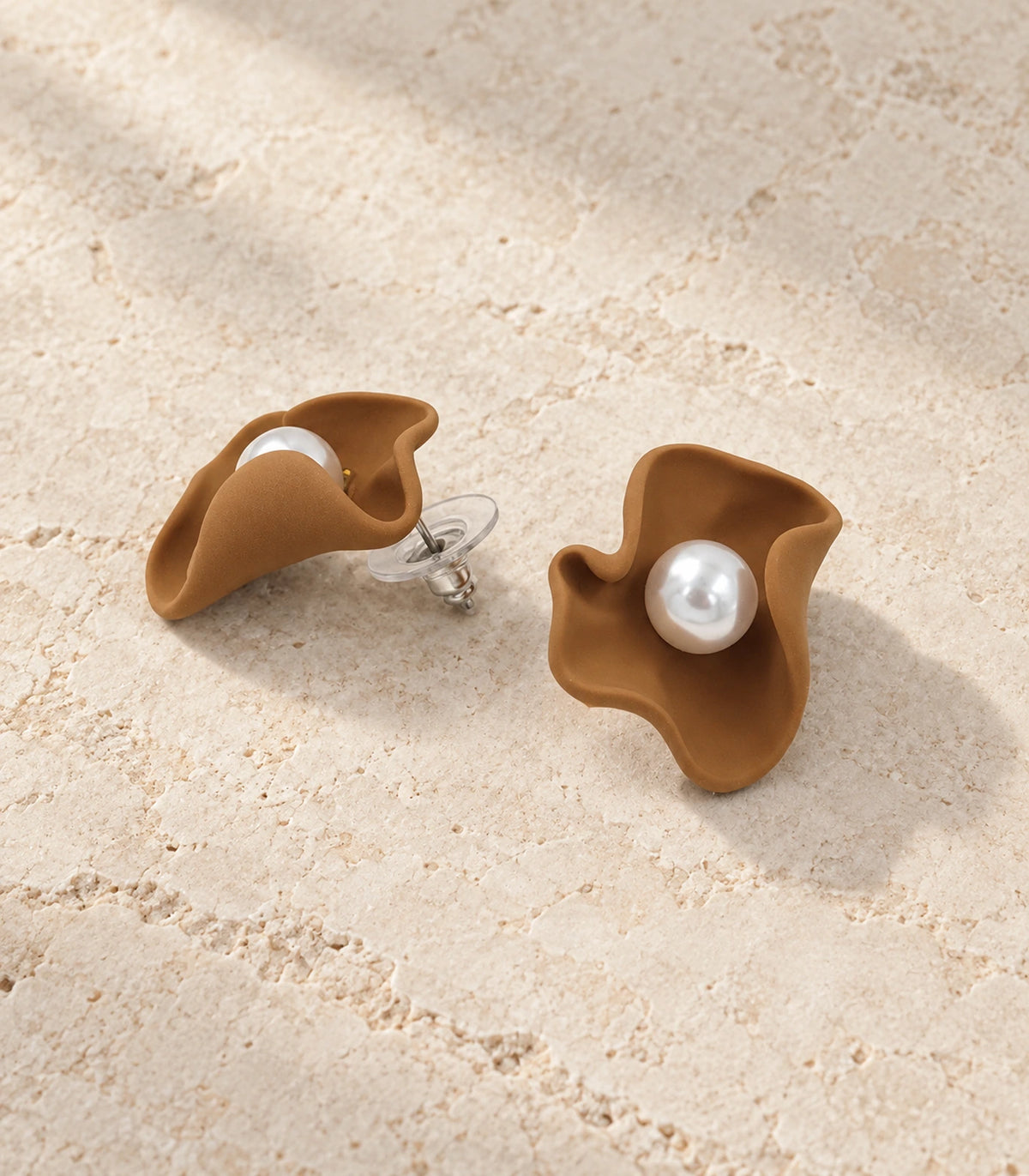 JIMIKI Folded Calla Pearl Stud Earrings, Camel — pair in a styled flat lay #color_camel