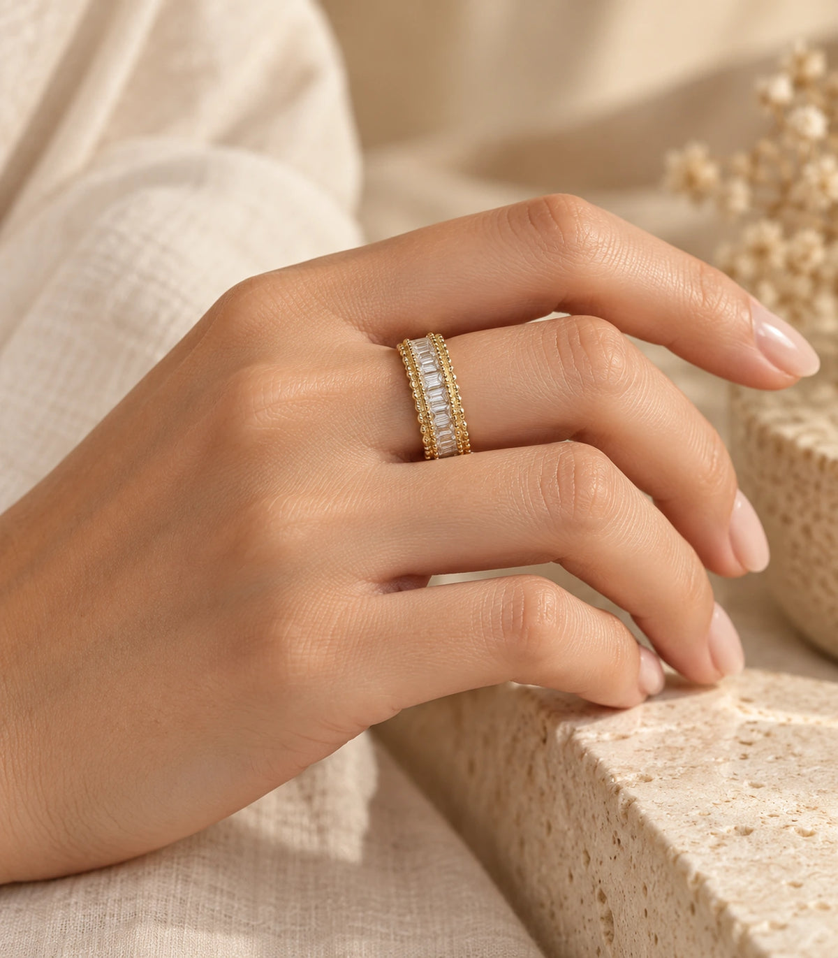 Gold-tone baguette-style ring worn in a bent-hand editorial pose