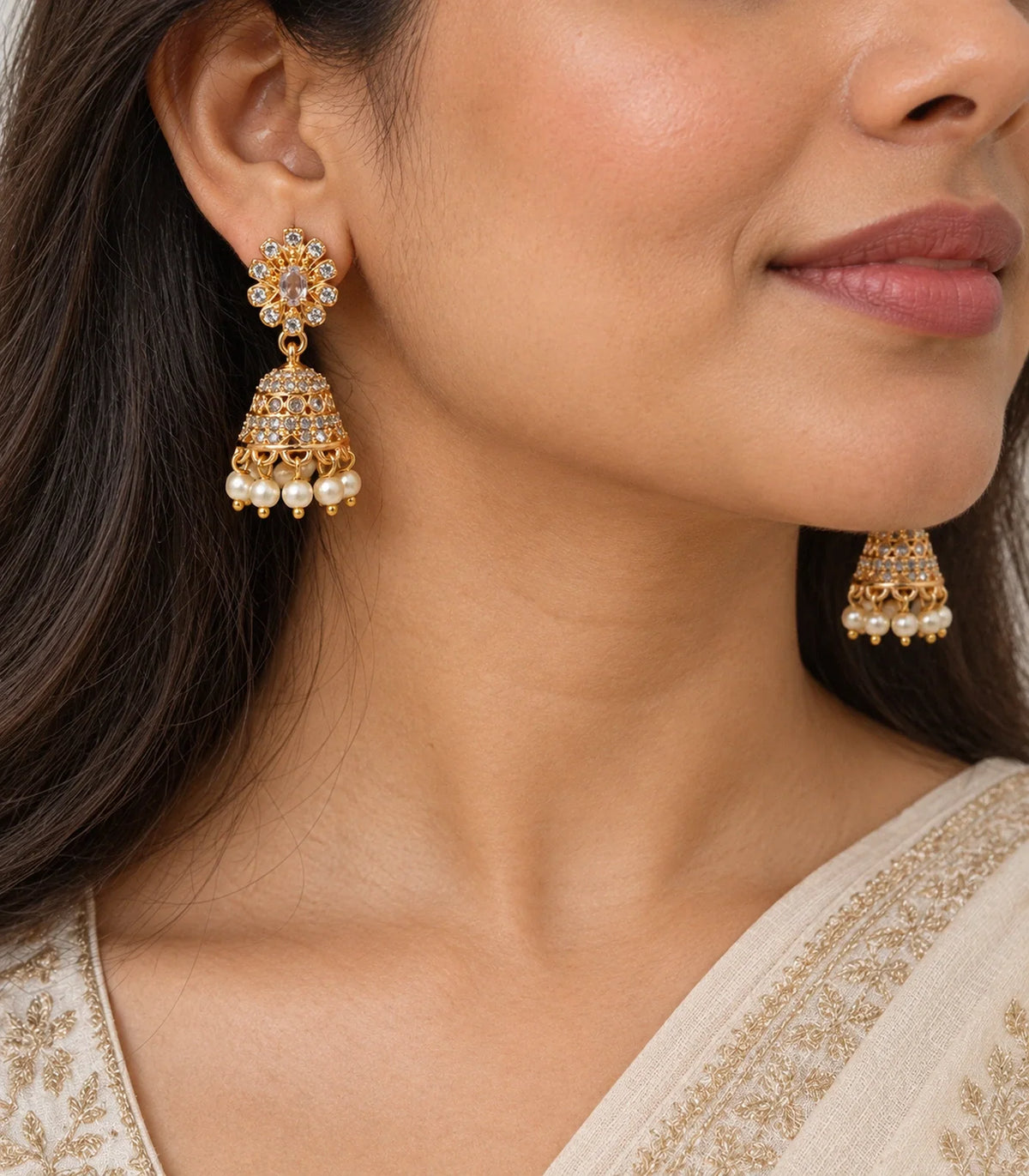 Close view of a champagne floral stud, patterned gold-tone dome and cream bead fringe worn at the ear
