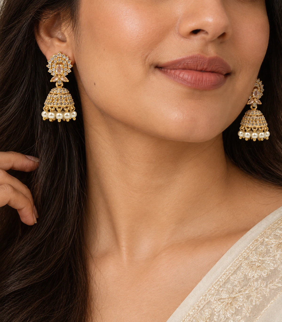 Close worn view of champagne oval halo studs, paired marquise details, clear stone bells and cream pearl-style fringe