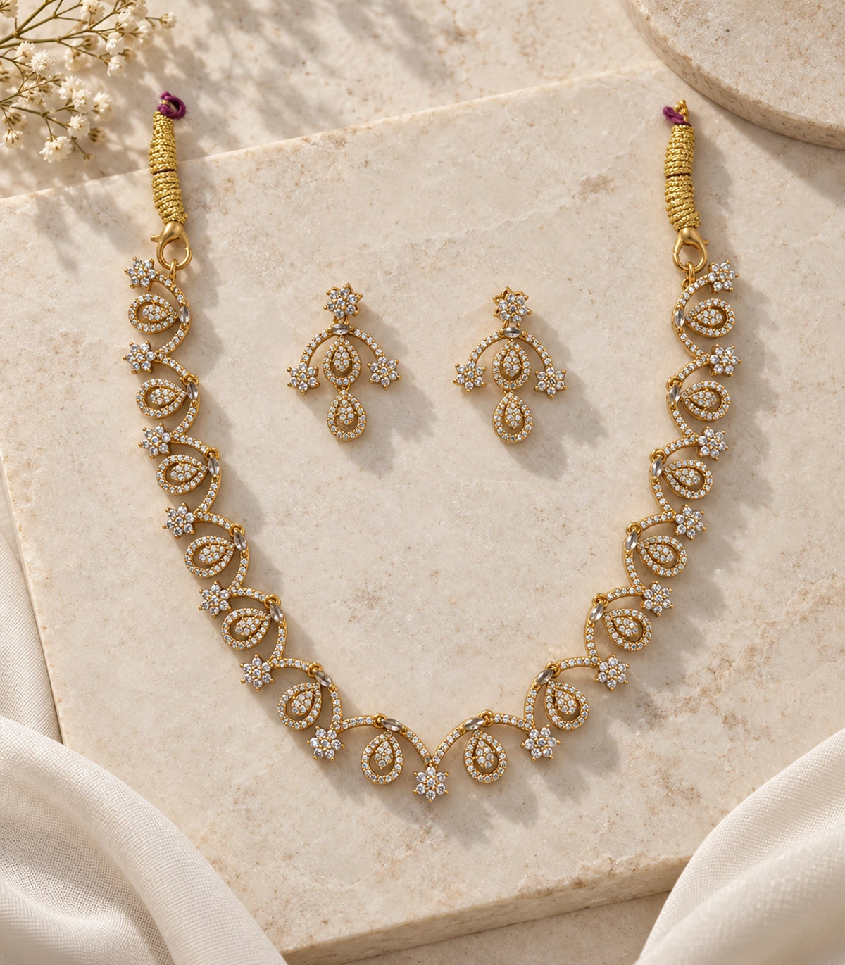 Gold Clear Loop Crystal Necklace Set with necklace and two matching earrings on a pale stone flatlay