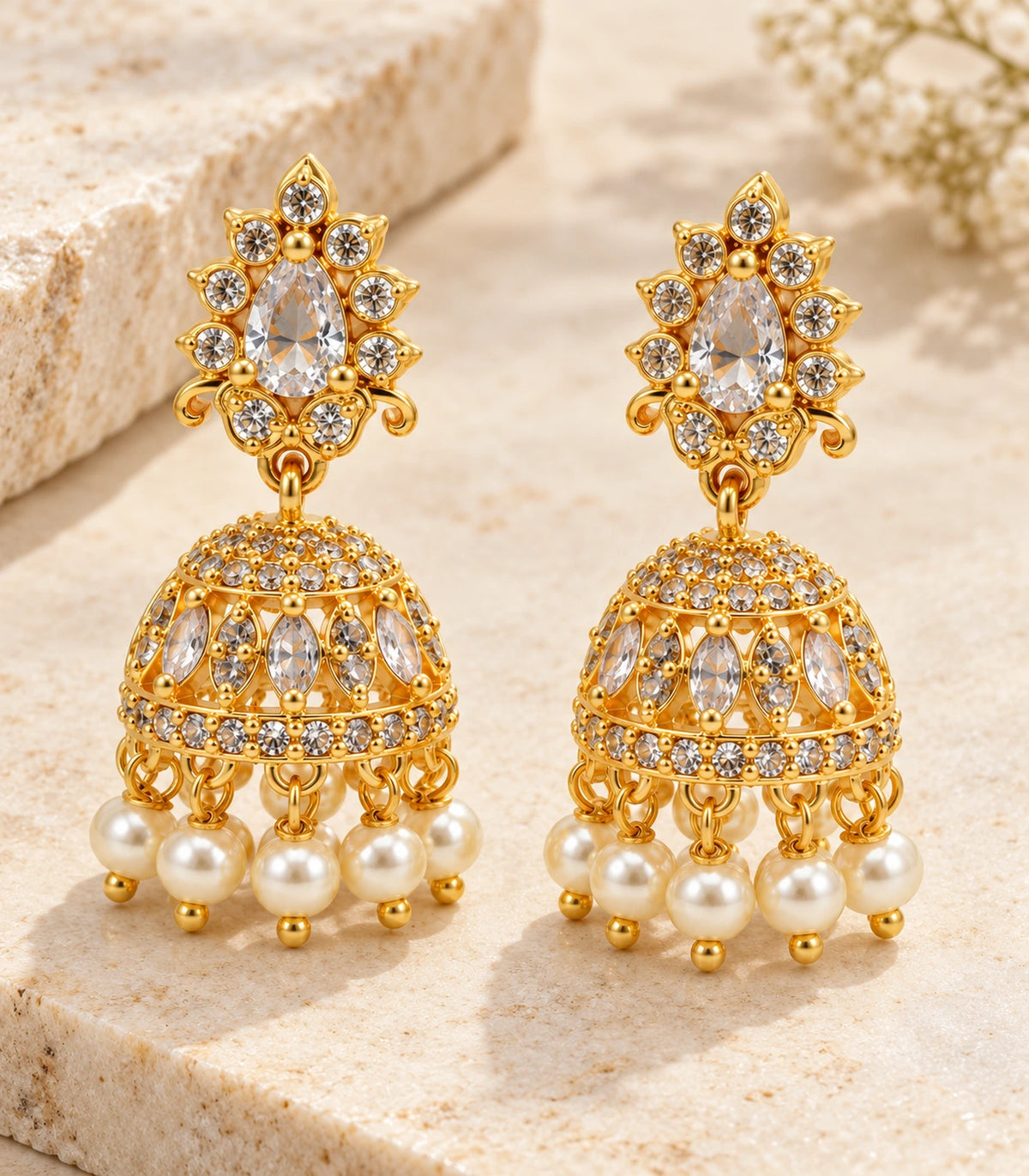 Gold-tone clear teardrop floral jhumka earrings pair in an editorial flatlay