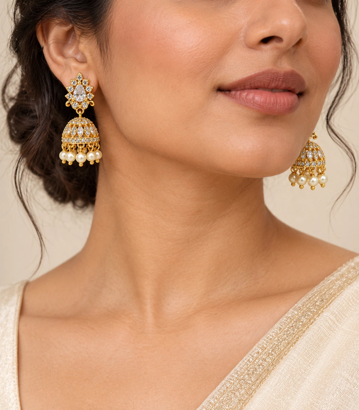 Gold-tone clear teardrop floral jhumka earrings worn by a model