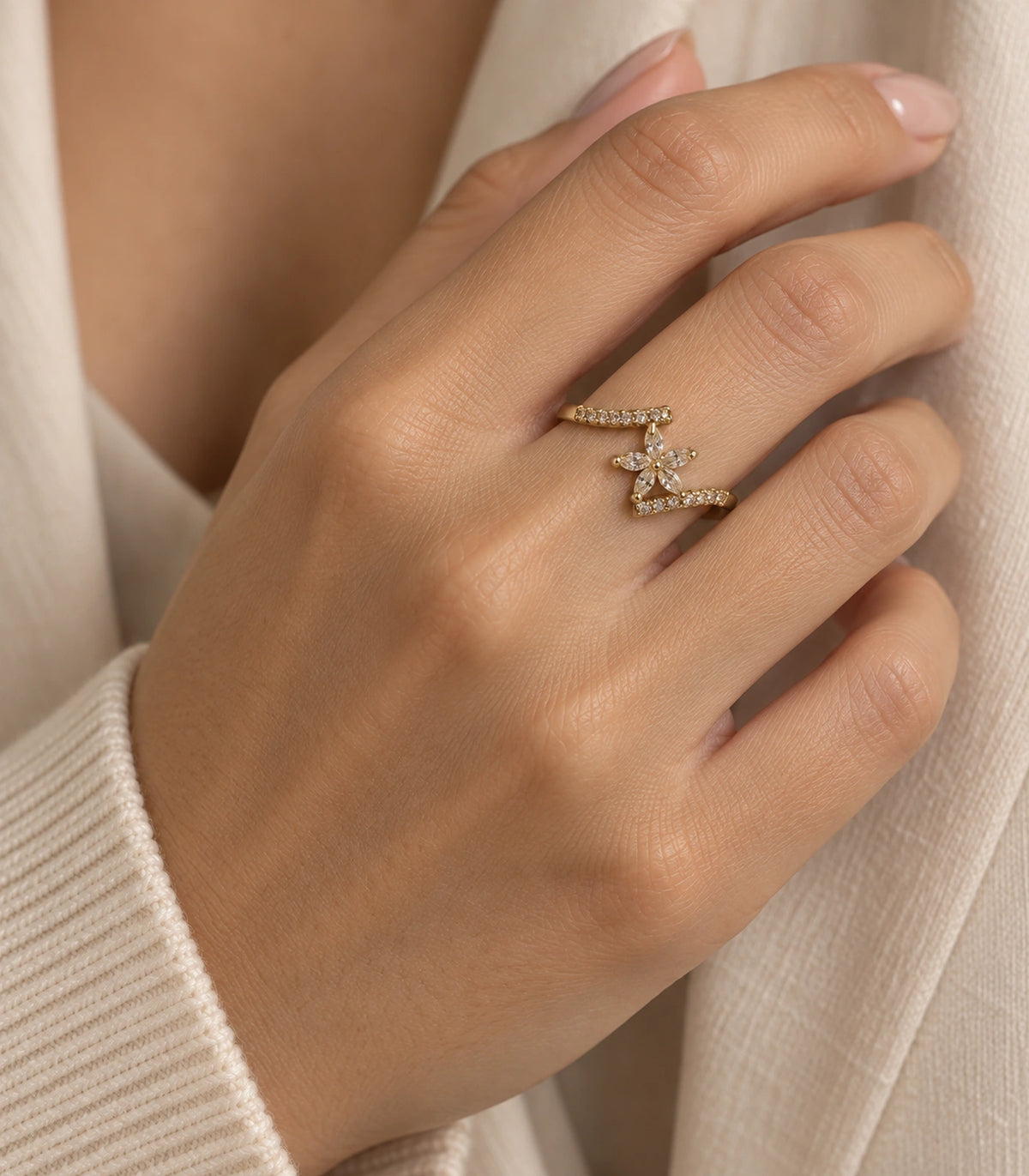 Gold-tone sweep ring worn in a second hand pose with cream clothing