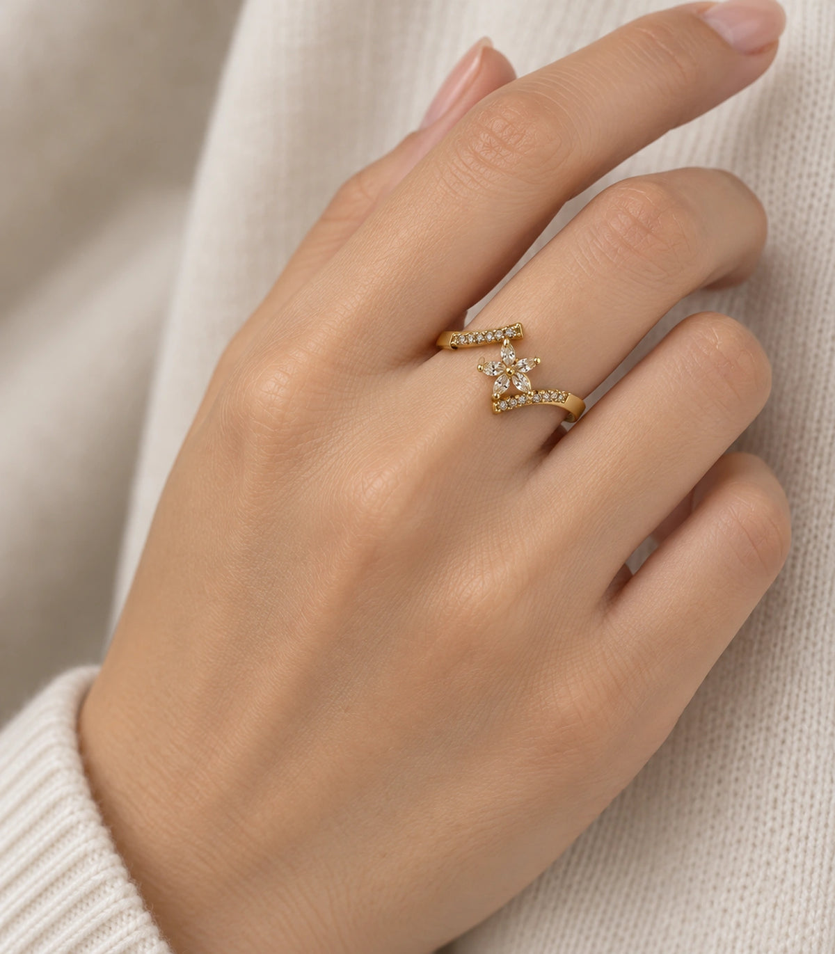Gold-tone sweep ring worn on a finger beside a cream cuff