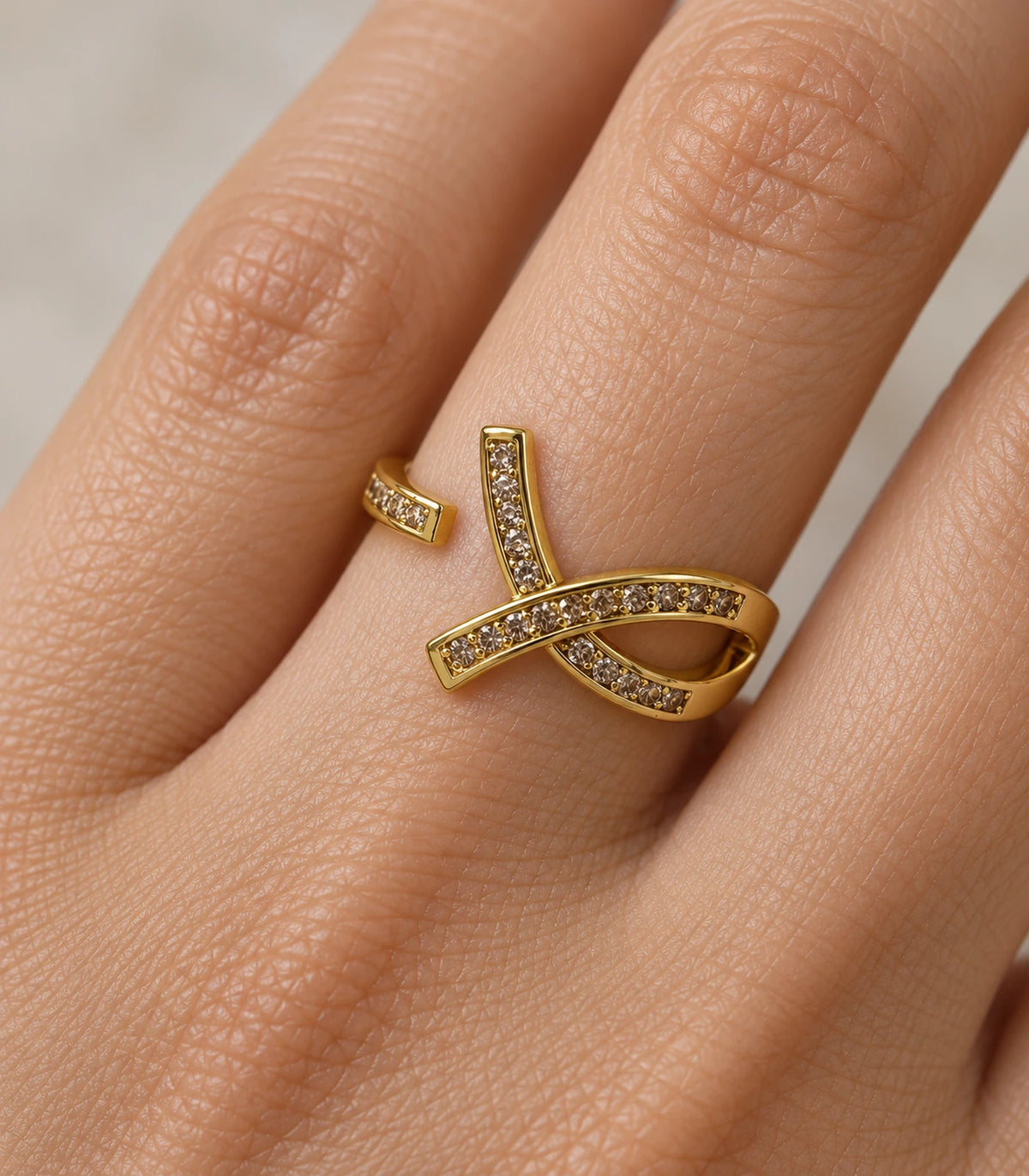 Closeup of Gold Crystal Crossing Ribbon Open Ring worn on a finger