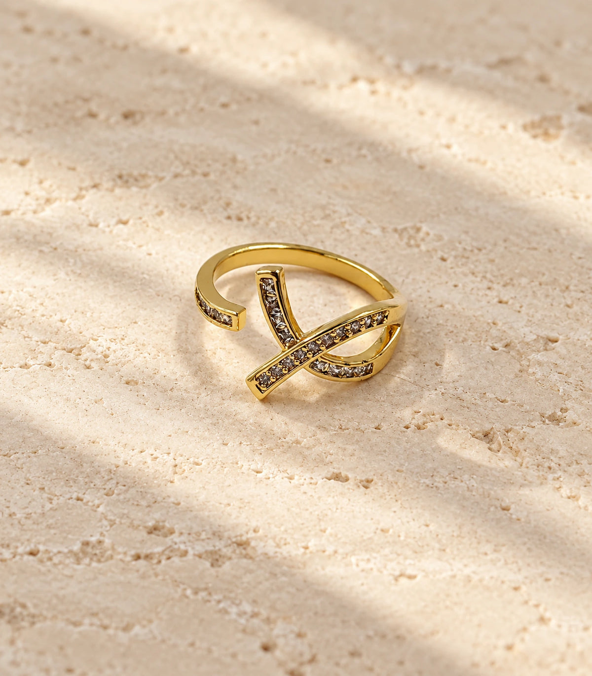 Gold Crystal Crossing Ribbon Open Ring on a neutral stone surface