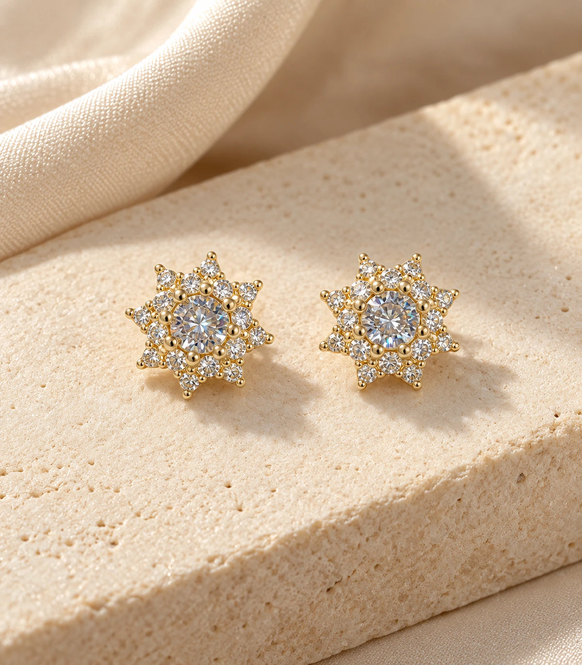 Matching gold-tone crystal sunburst stud earrings styled on a stone surface