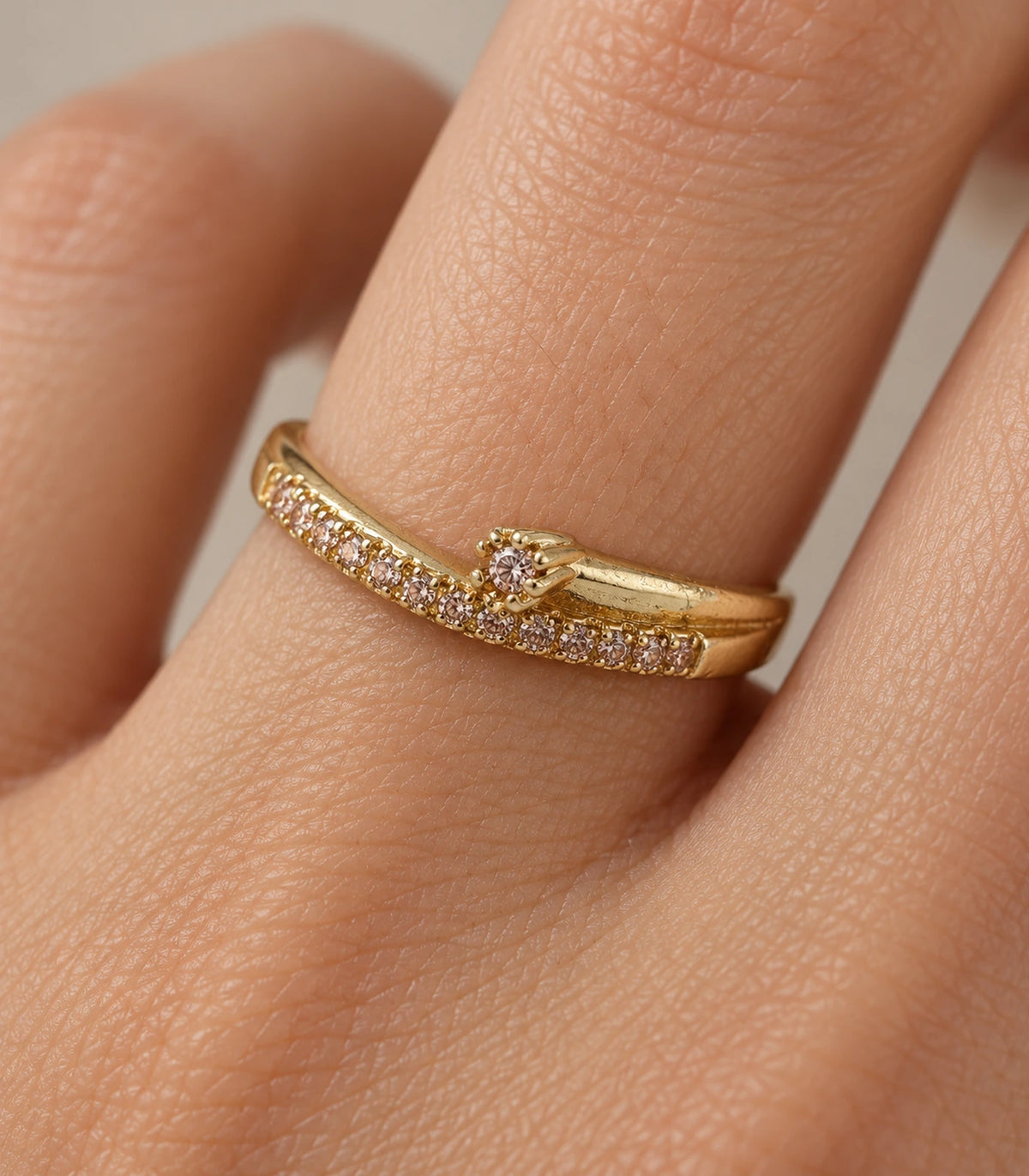 Closeup of the gold-tone wishbone arrow ring worn on a finger, showing the crystal-style row and raised tip