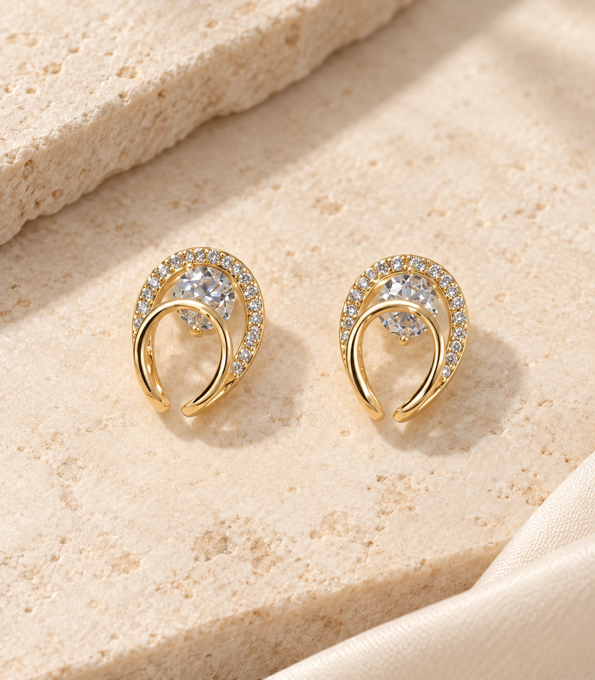 Matching pair of gold-tone double-loop stud earrings styled on pale stone