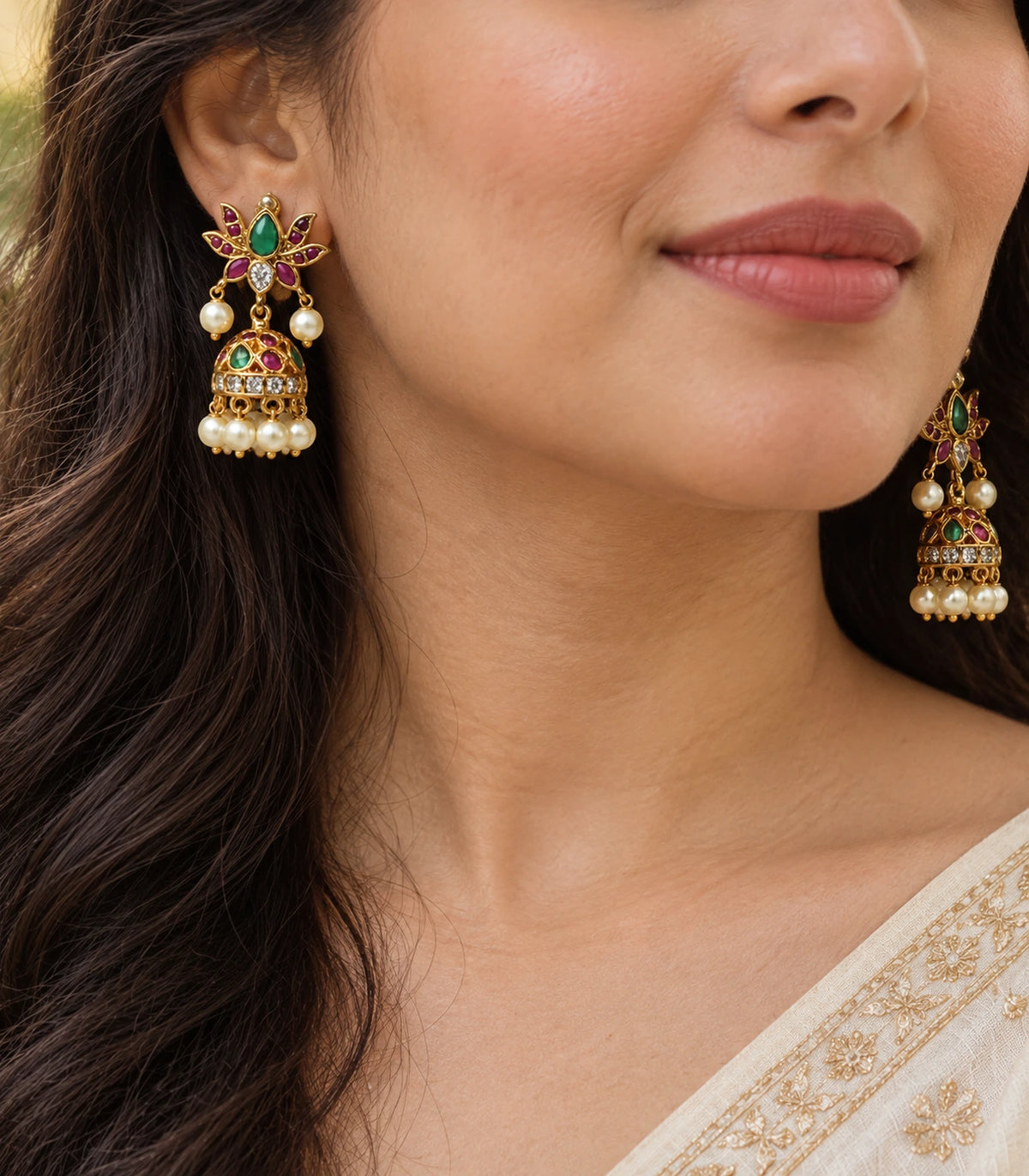 Close view of gold green and magenta lotus jhumka earrings worn at the ears