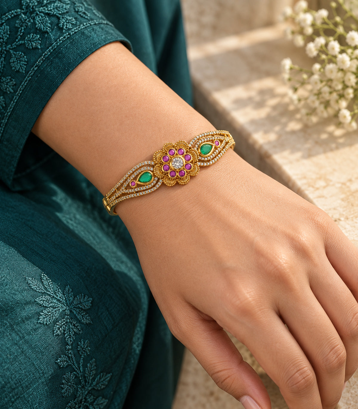 Gold magenta and green teardrop bangle worn in an editorial setting