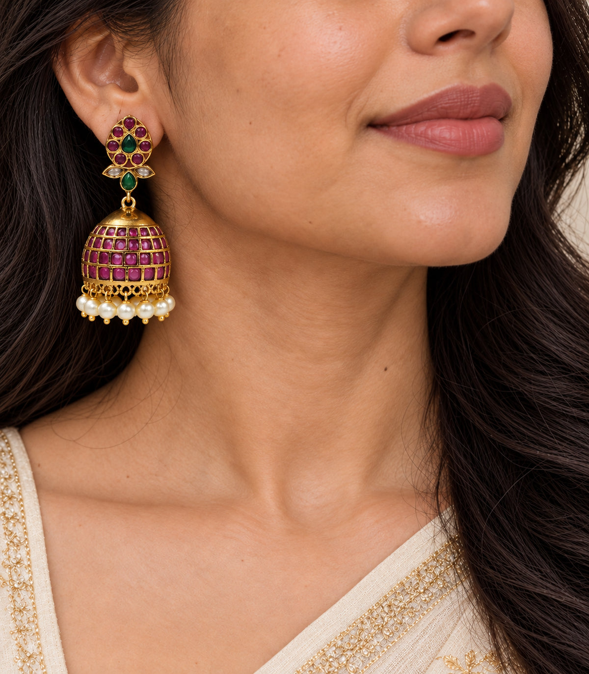 Single worn jhumka closeup showing green teardrops, clear leaf details and four magenta grid rows