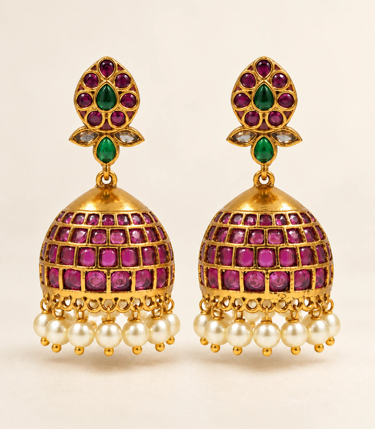 Complete matching pair of magenta and green pearl-fringe jhumka earrings on a warm neutral surface