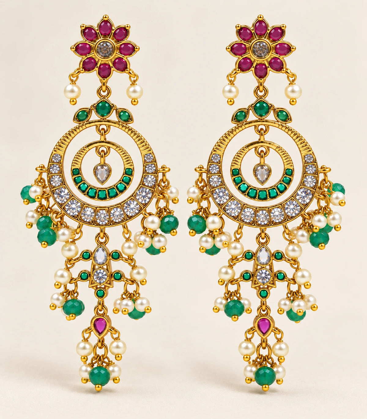 Complete pair of gold-tone magenta and green chandelier earrings in a neutral flatlay