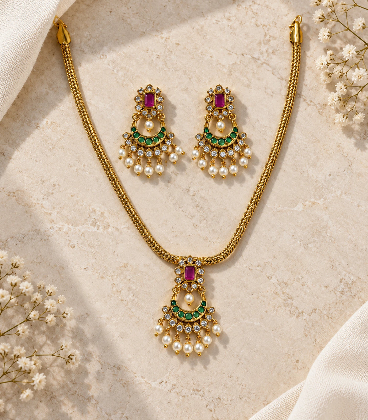 Complete necklace and matching earring pair arranged on a cream stone background
