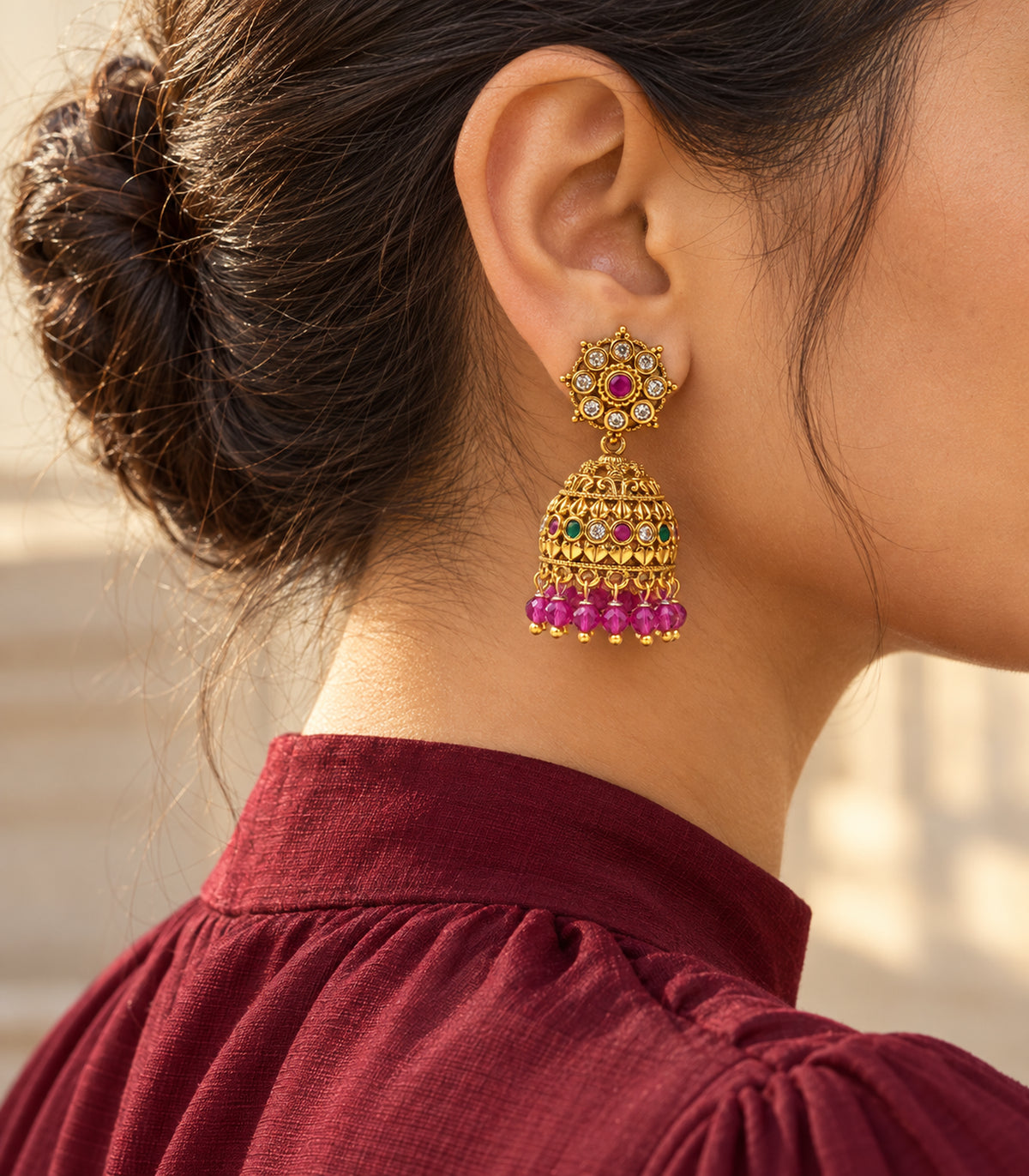 Gold-tone magenta bead jhumka earring styled with a burgundy high neckline