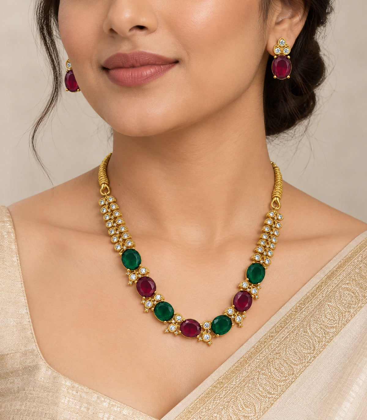 Gold-tone magenta and green oval necklace set worn with matching earrings and an ivory outfit