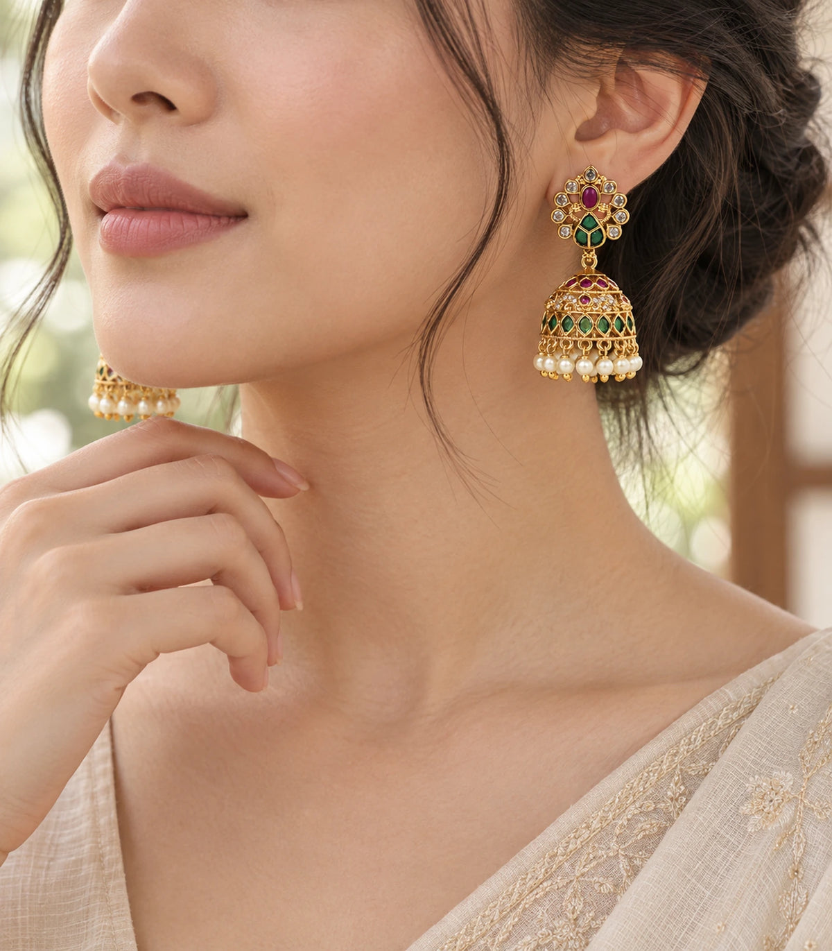 Three-quarter worn view of a gold-tone peacock jhumka earring with magenta and green accents