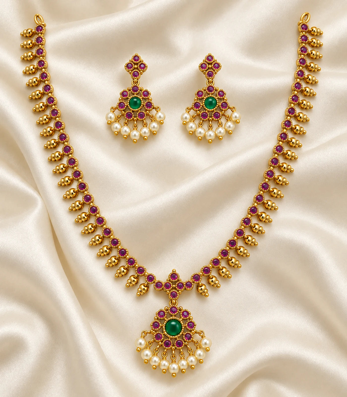 Complete gold-tone magenta and green necklace set with matching earrings on ivory fabric