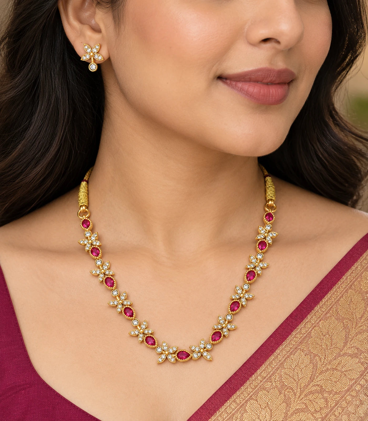Close view of the magenta teardrop and clear four-leaf necklace worn with a matching clear earring