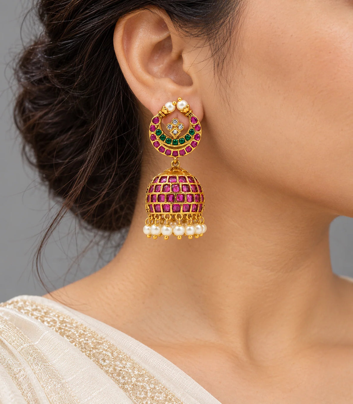 Gold-tone magenta and green circular lattice jhumka earrings worn with an ivory outfit