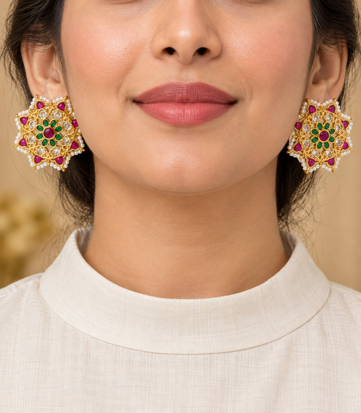 Close detail of gold magenta and green floral stud earrings with white pearl border