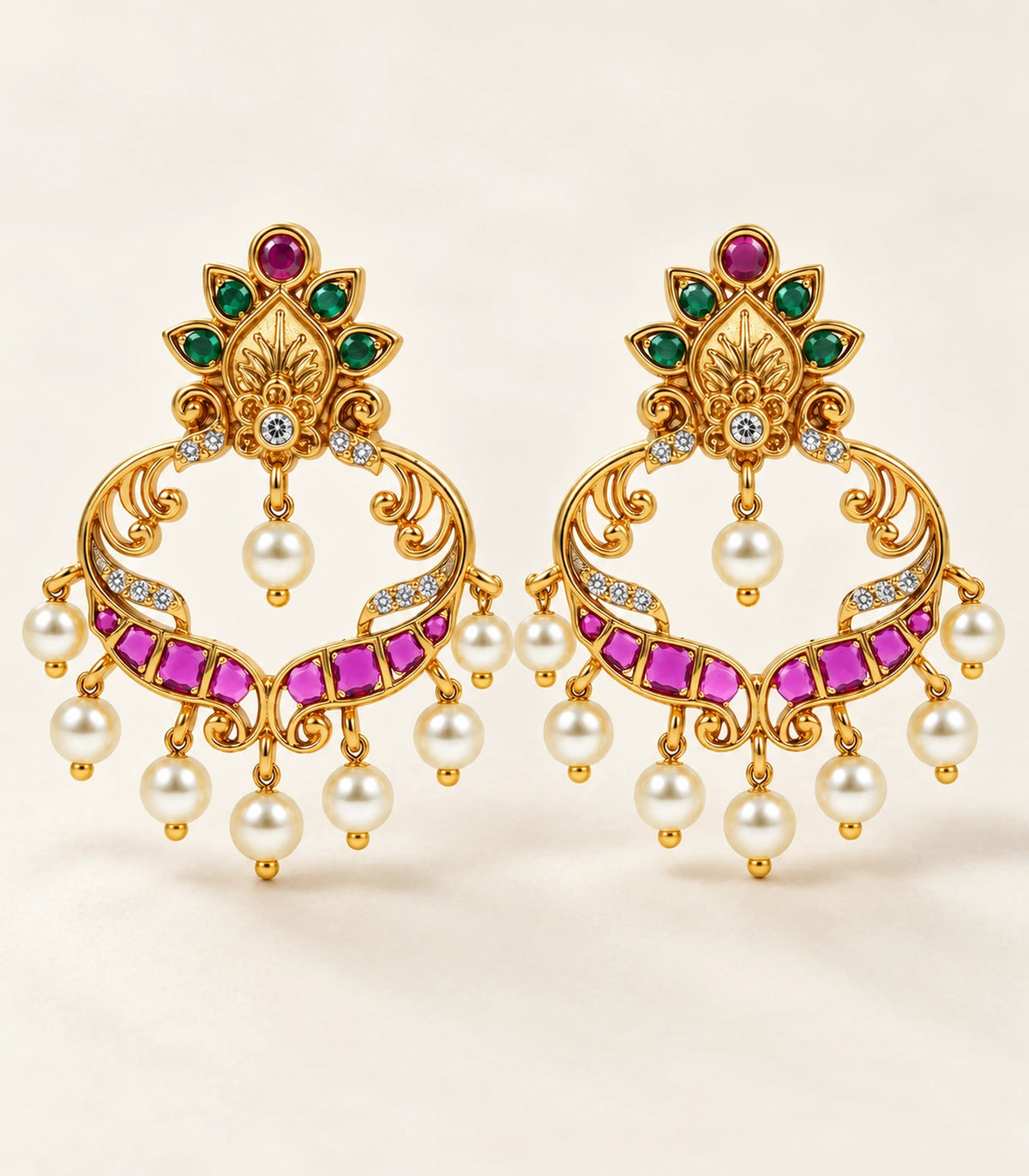 Complete pair of gold magenta and green pearl-drop earrings on a light fabric background