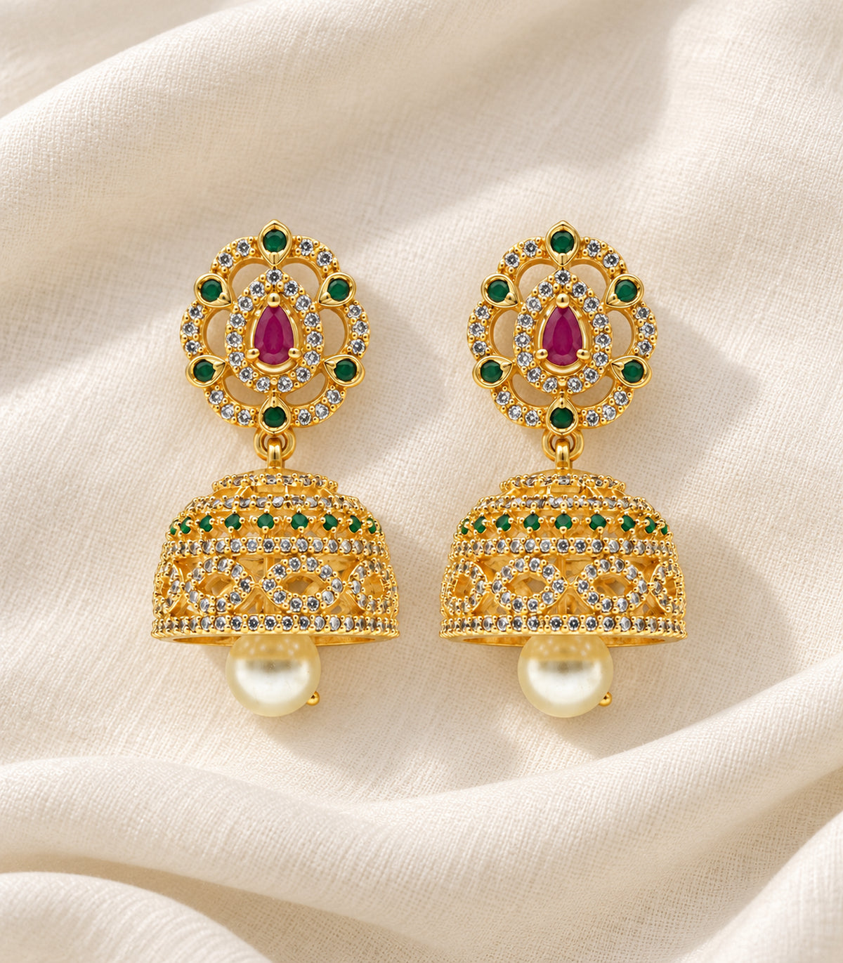 Complete pair of magenta and green teardrop pearl jhumka earrings in a styled flat lay