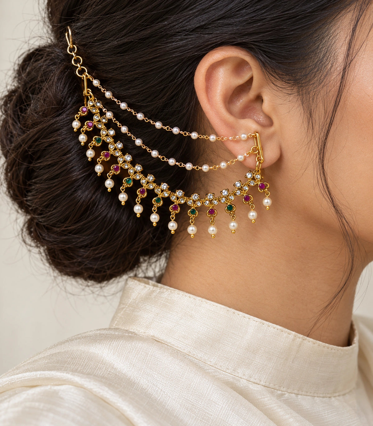 Close view of triple-leaf pearl ear chain worn with an ivory silk collar