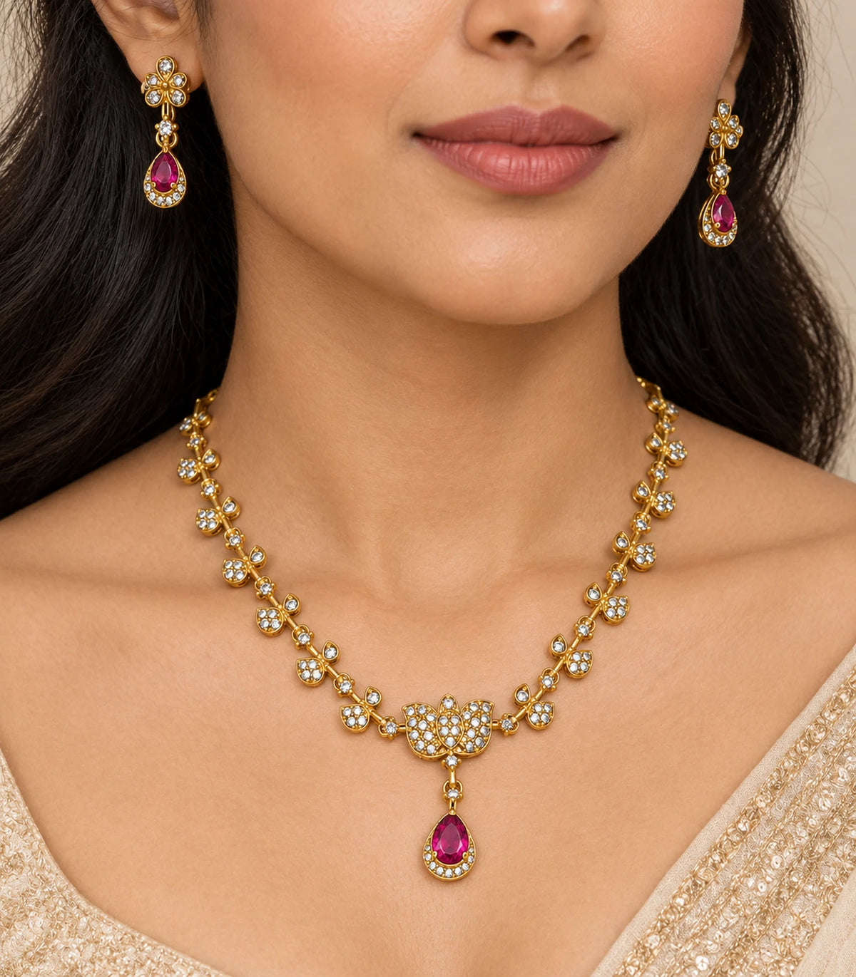 Close view of the gold-tone leaf necklace, clear crystal-style details and magenta teardrop earrings worn naturally