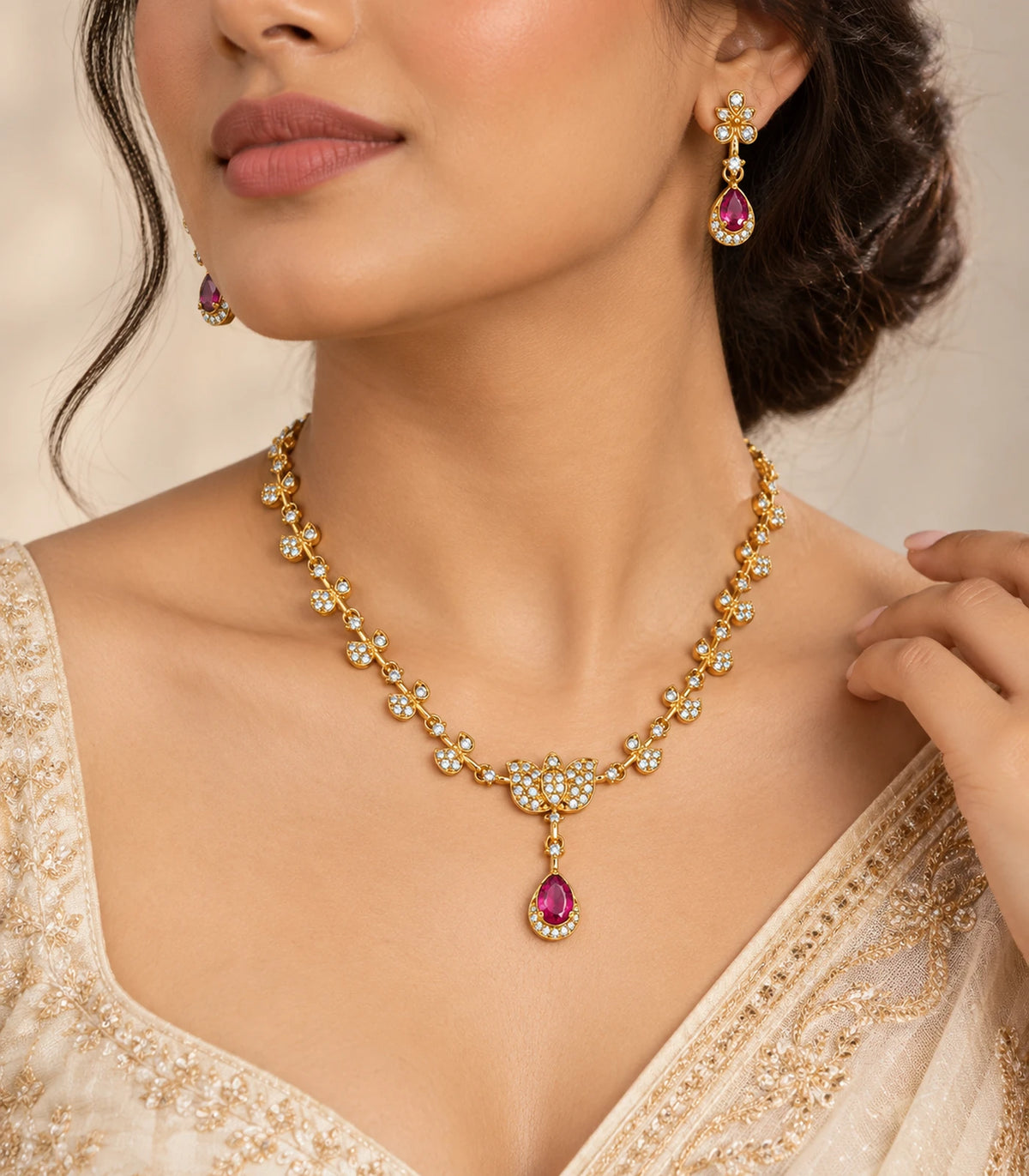 Three-quarter worn view of the gold-tone leaf necklace and magenta teardrop earrings with ivory occasion styling