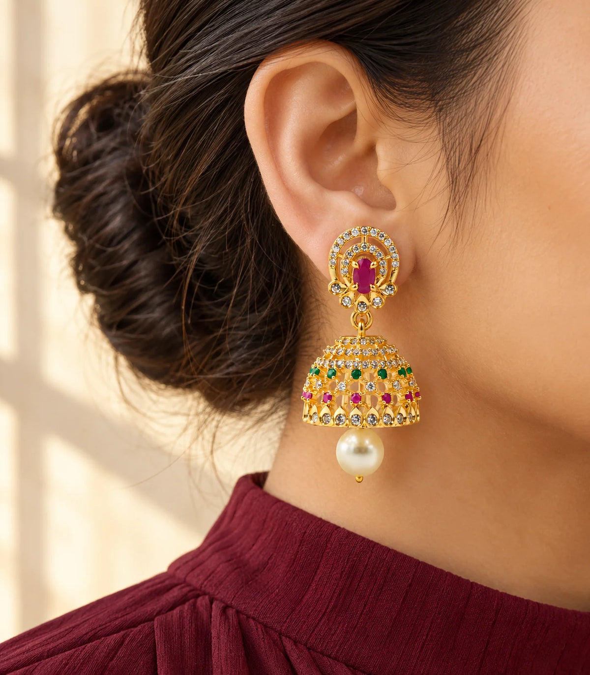 Gold-tone magenta and green jhumka earrings styled with a cream patterned high-collar outfit