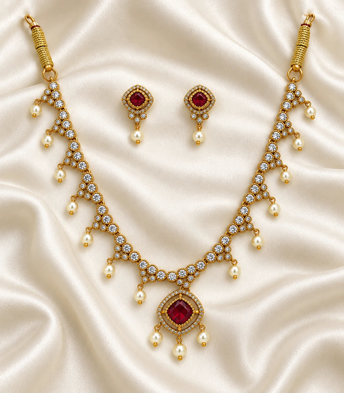 Gold-tone magenta necklace and matching pair of earrings arranged on ivory fabric