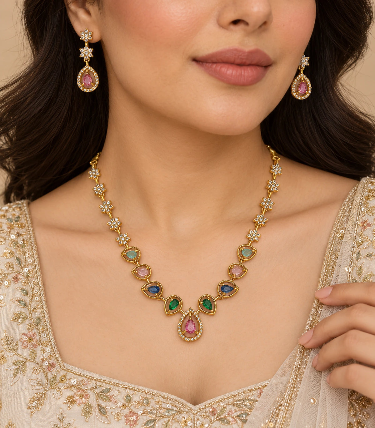 Gold-tone multicolour necklace and pink-drop earrings worn with a cream embroidered outfit