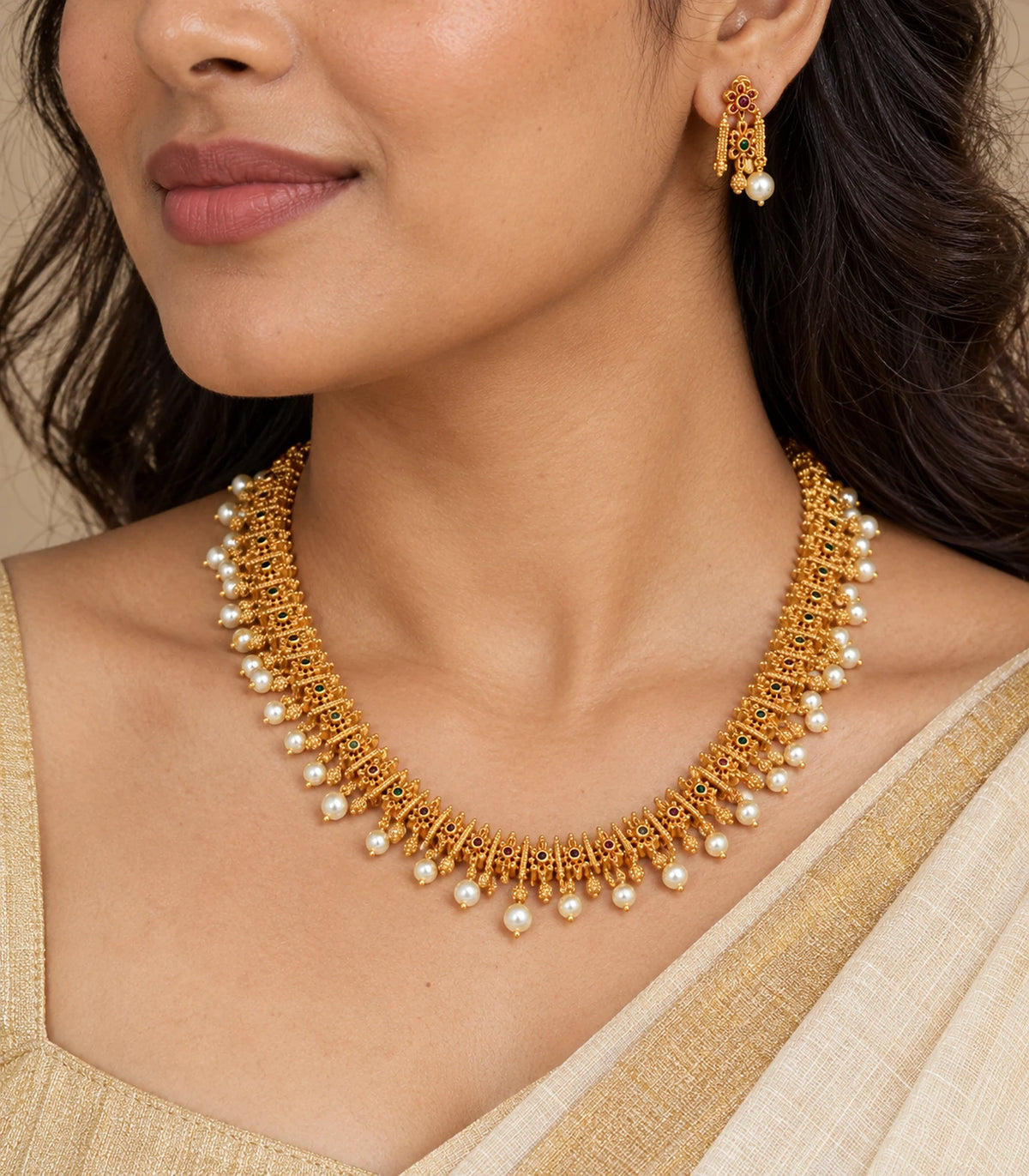 Close view of gold-tone floral necklace and matching pearl-look drop earring