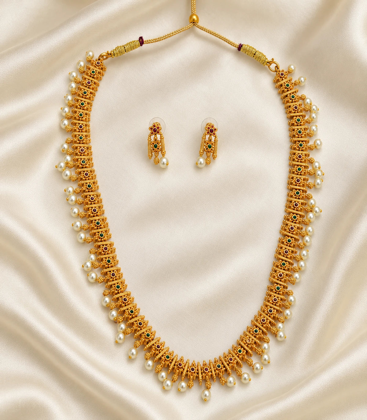 Gold multicolor pearl fringe necklace and matching earring pair arranged on cream fabric