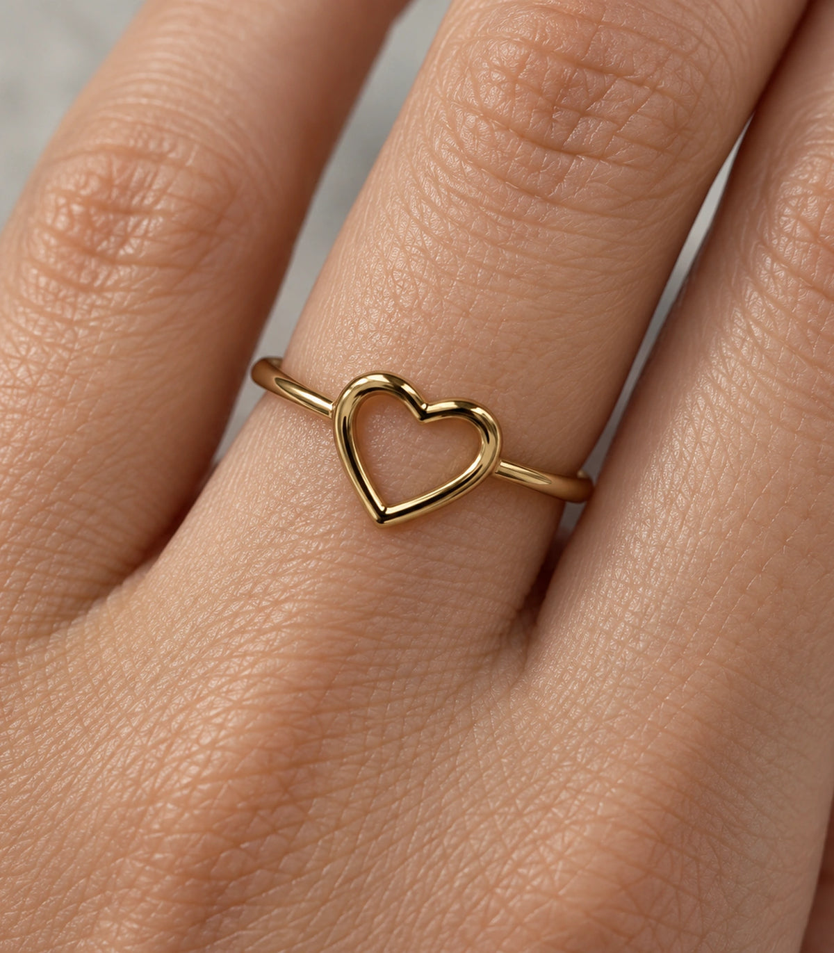 Close view of the hollow heart outline and gold-tone band on a finger